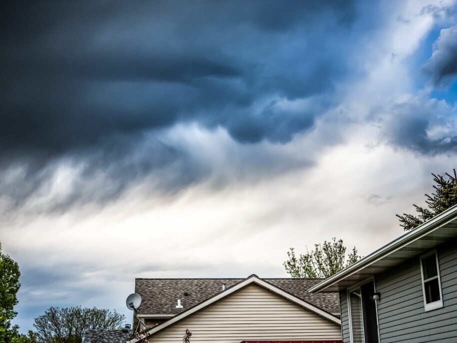 Dark storm clouds over suburban homes—Rooftecco provides storm damage roof inspections and emergency repair services.