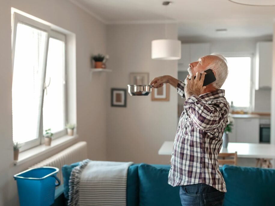 Worried homeowner calling for emergency roof repair while catching a ceiling leak—Rooftecco responds quickly to storm damage and roof leak emergencies.